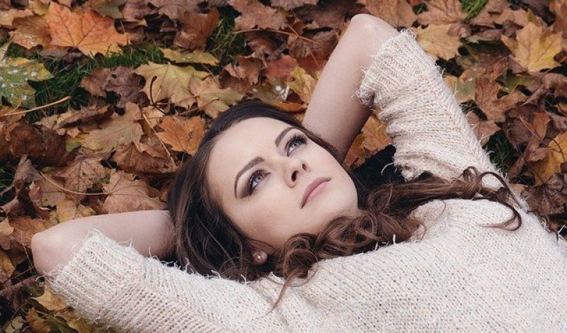 Woman lying in autumn leaves, Skelian Chiropractic Clinici
