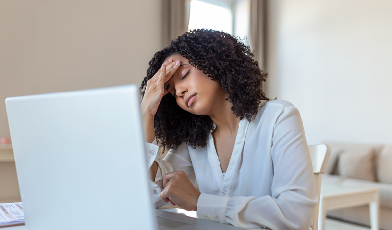 Lady at laptop with headache, Chiropractor Cheltenham